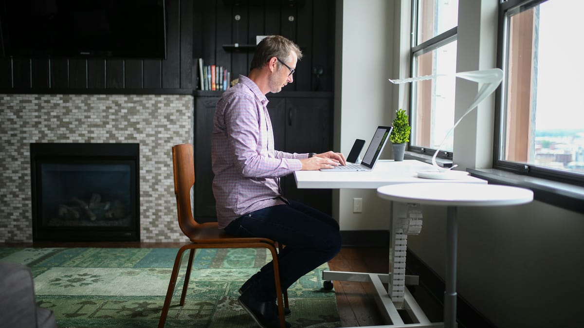 A man working at a desk by a large window in a calm home office