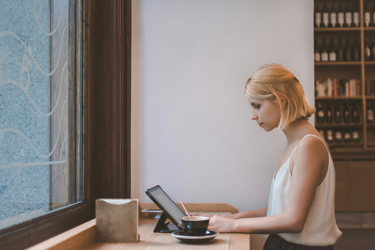 A woman working on a tablet at a calm, sunlit desk